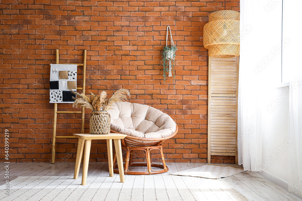 Stylish armchair and table with pampas grass in interior of living room