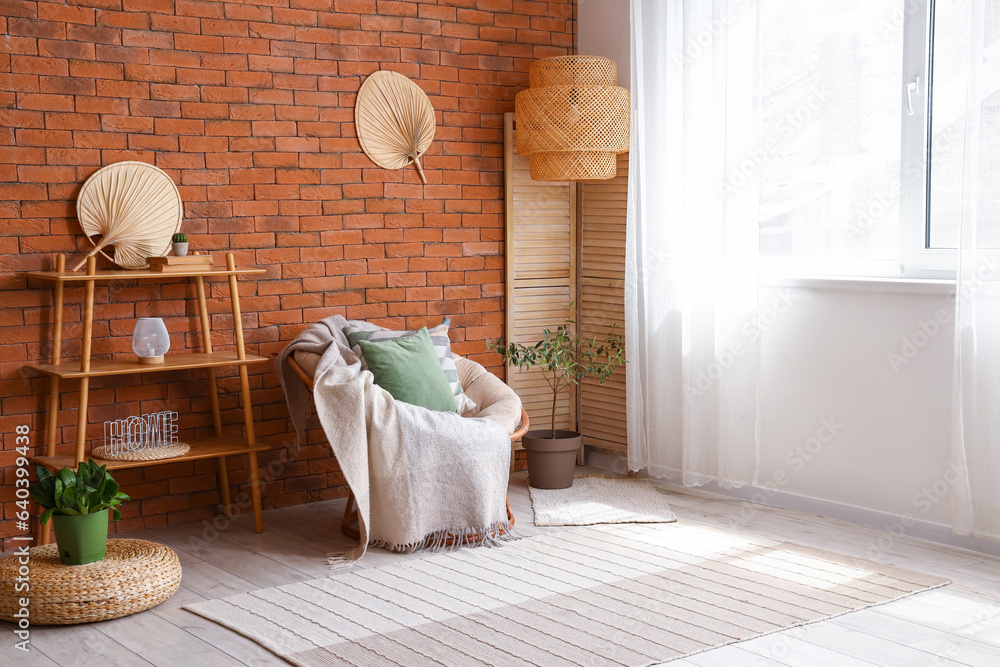 Stylish armchair with cushion and blanket in interior of light living room