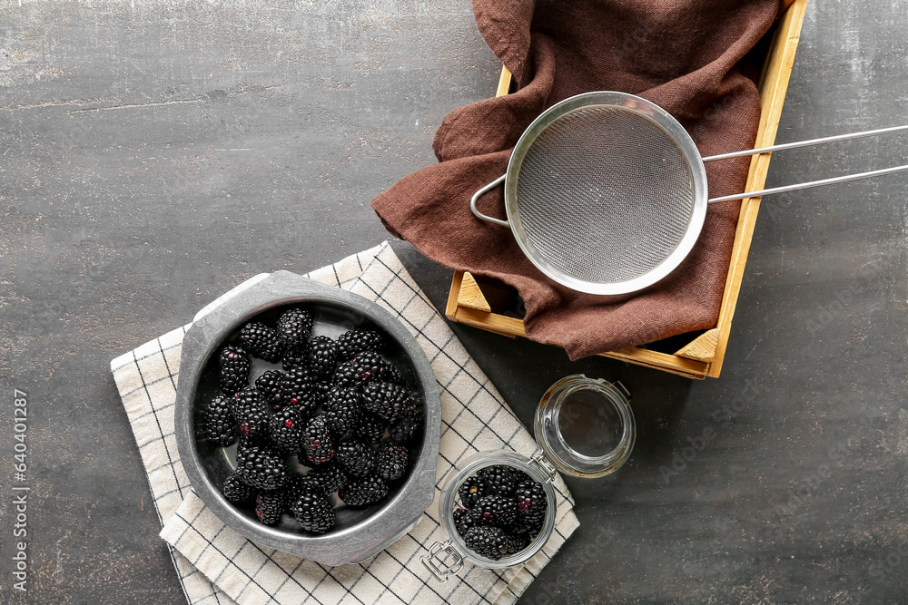 Metal bowl and jar with fresh blackberries on grey background