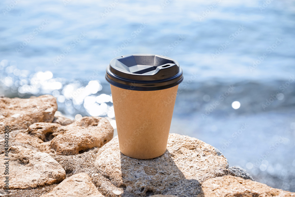 Takeaway cup of hot coffee on beach