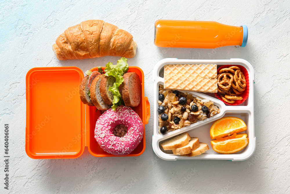 Lunchboxes with different delicious food and bottle of juice on gradient background