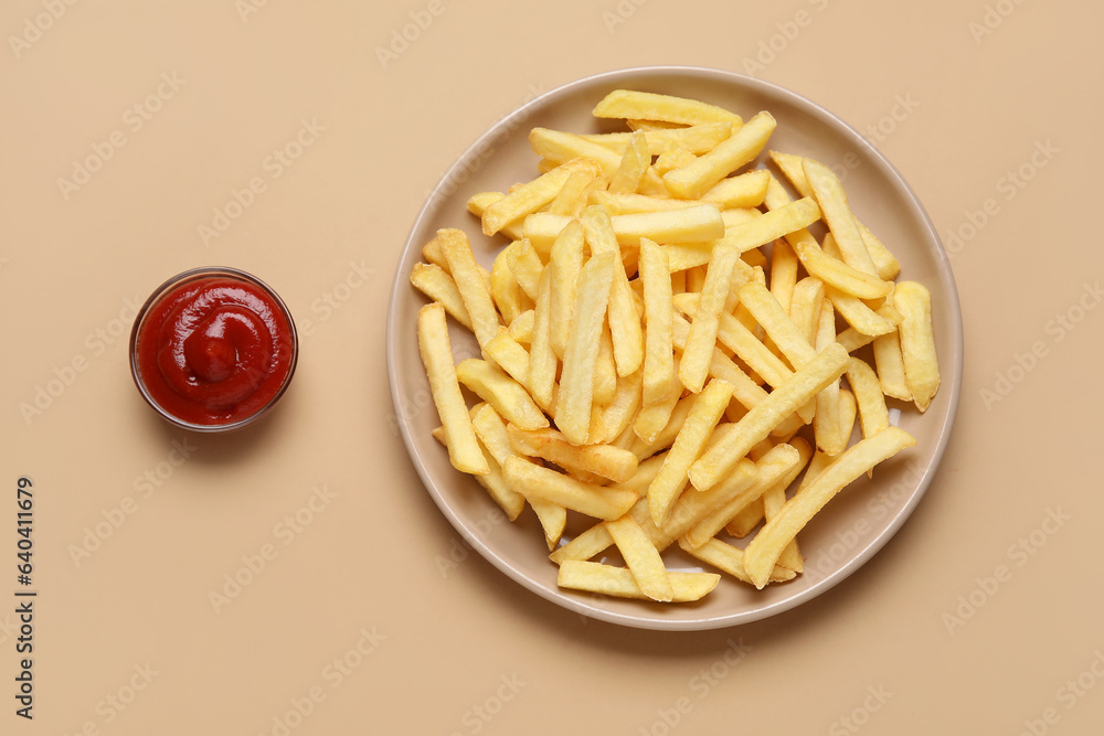 Plate with golden french fries and ketchup on beige background