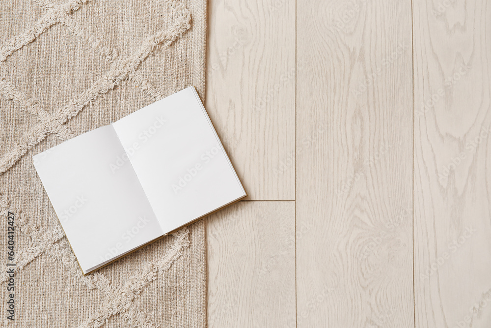 Book with blank pages on stylish rug in living room, closeup