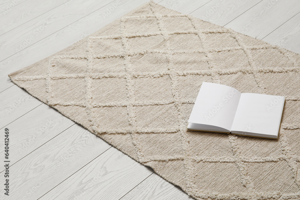 Book with blank pages on stylish rug in living room, closeup