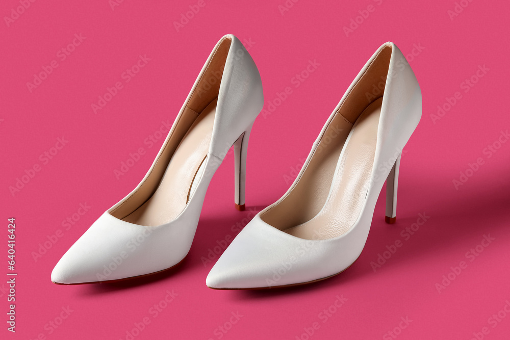 Stylish white high heels on pink background