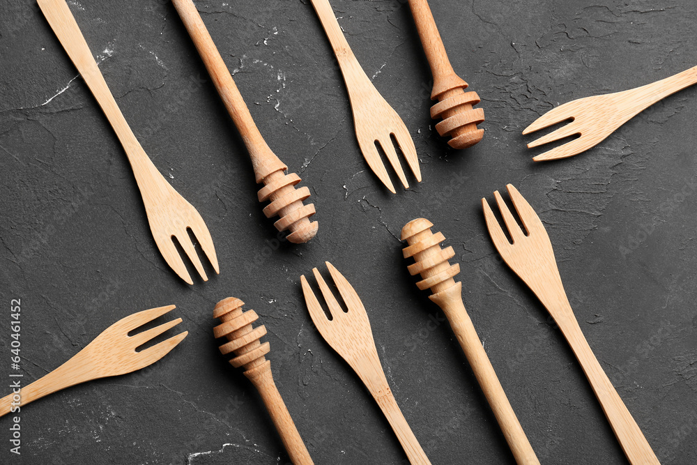 Wooden honey dippers and forks on black background