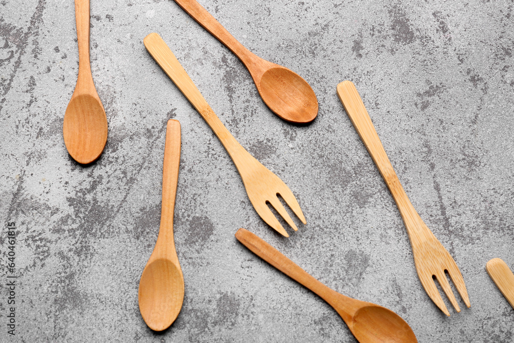 Wooden spoons and forks on grey background