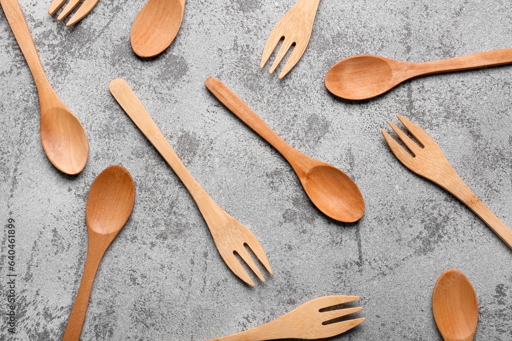 Wooden spoons and forks on grey background