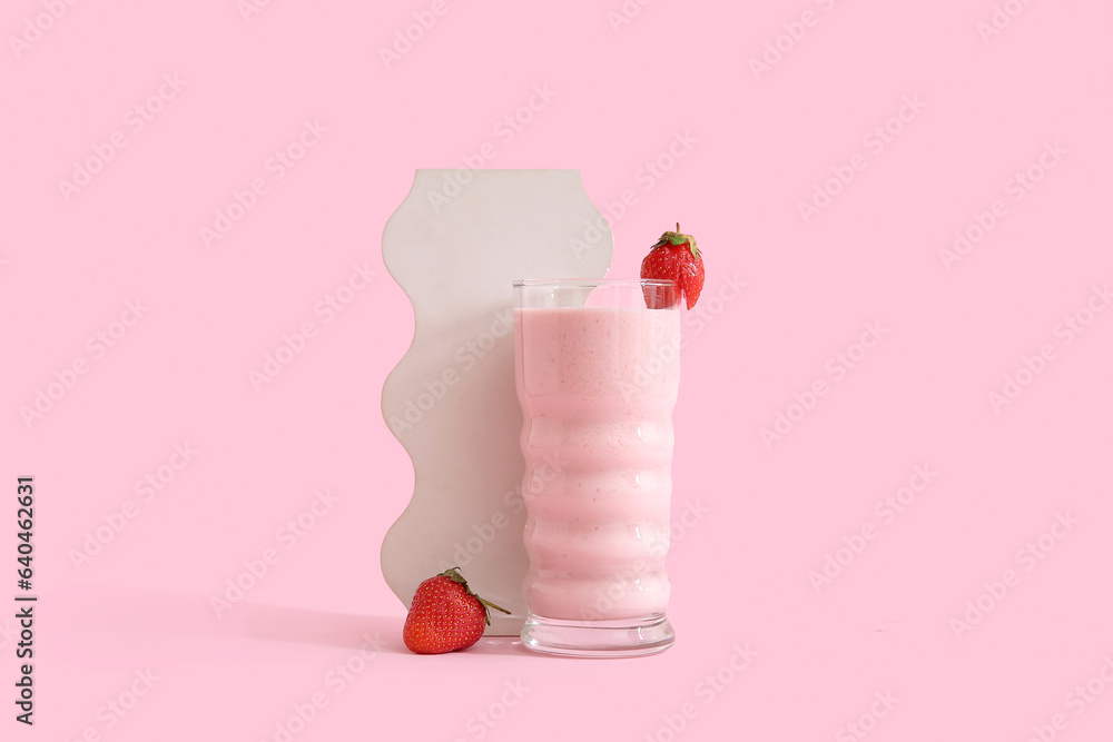 Glass of tasty strawberry smoothie on pink background