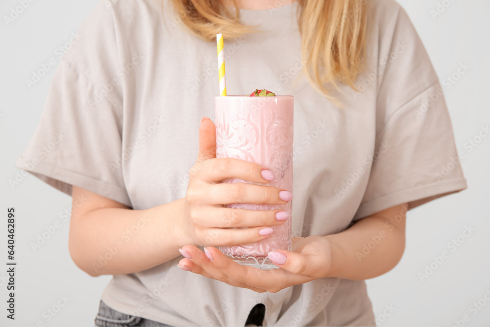 Woman holding glass of tasty strawberry smoothie on white background