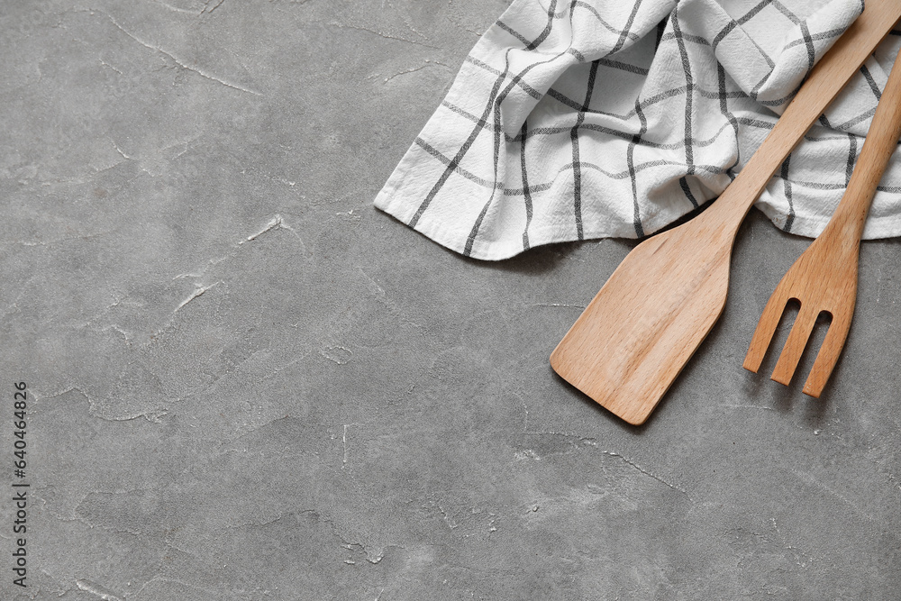 Wooden spatula, fork and napkin on grey background