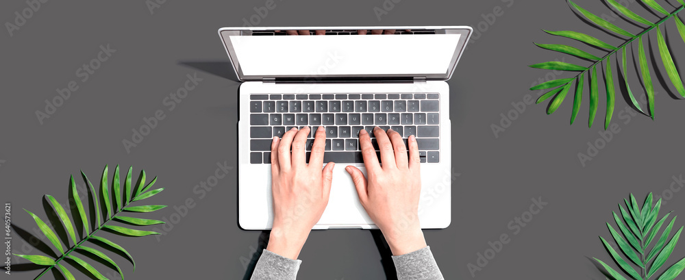 Person using a laptop computer with tropical leaves from above