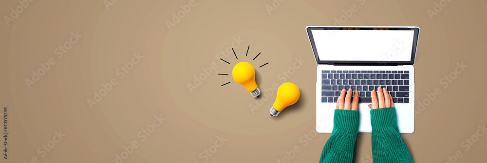 Person using a laptop computer and light bulbs - Flat lay