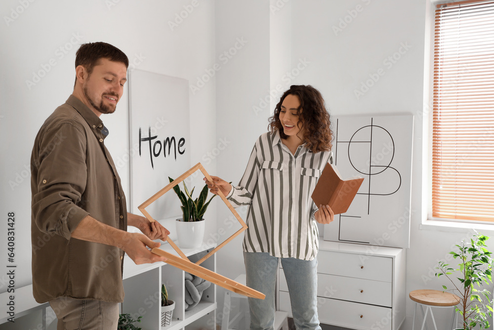 Young couple hanging frames at home