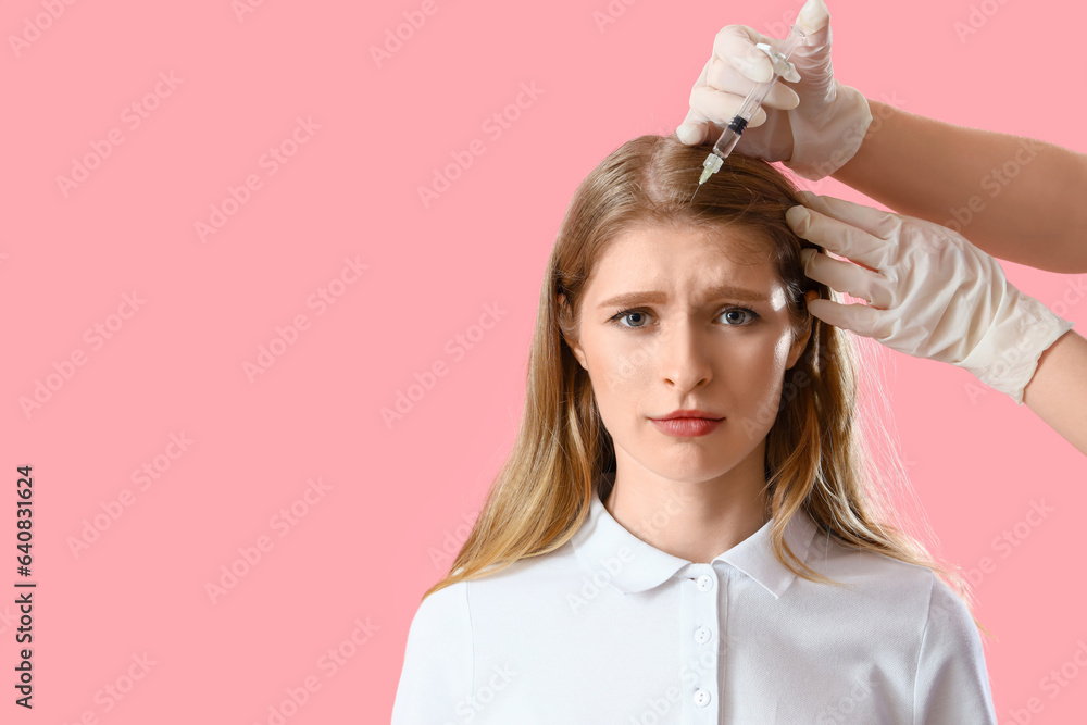 Young woman with hair loss problem receiving injection on pink background