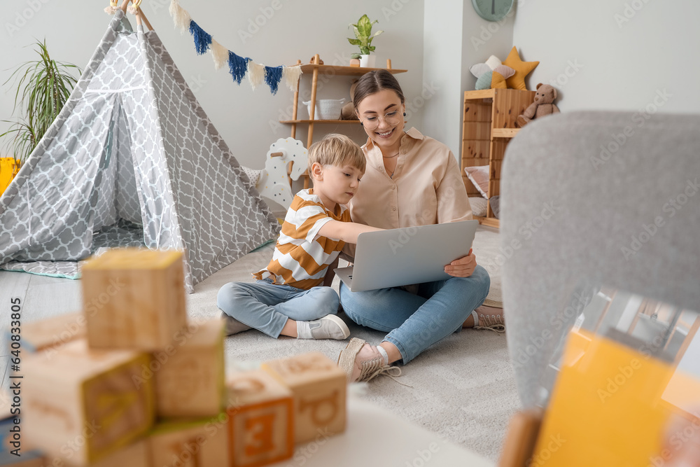 Nanny with little boy watching cartoons at home