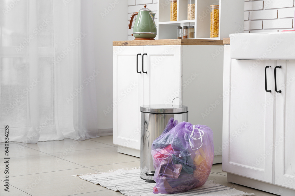 Trash bin and full garbage bag in interior of modern kitchen