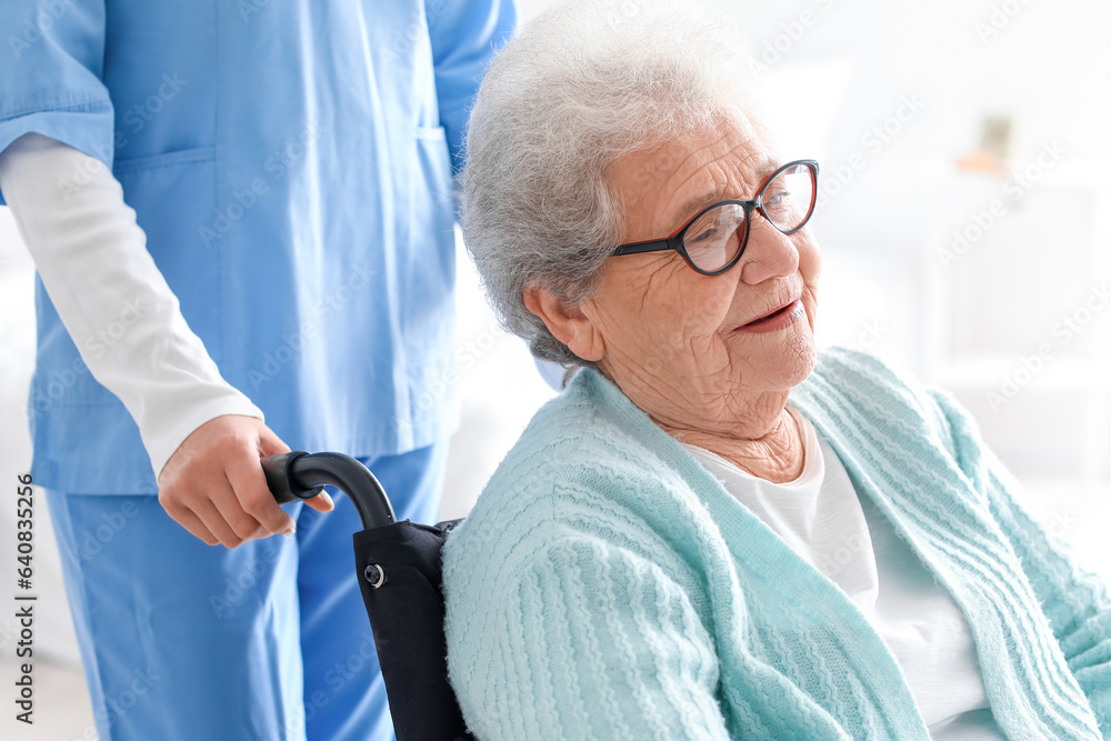 Senior woman in wheelchair with caregiver at home, closeup