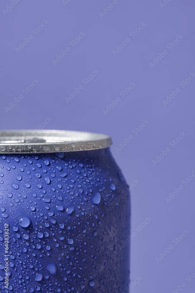 Can of fresh soda with water drops on lilac background, closeup