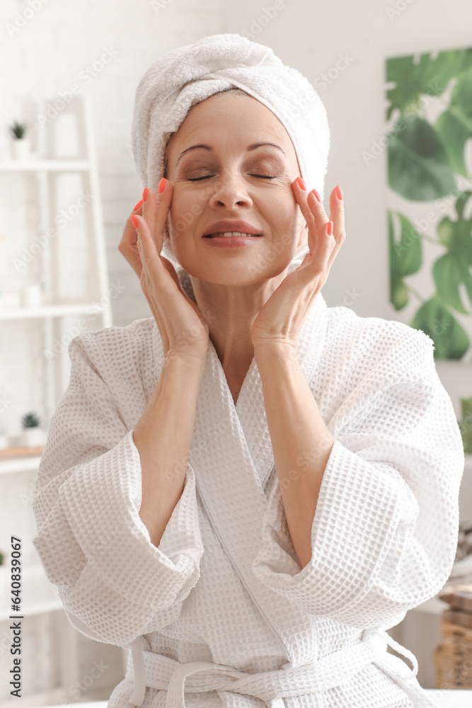 Mature woman applying facial cream in bathroom, closeup