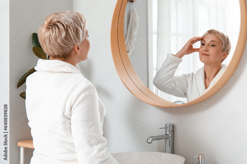 Mature woman looking in mirror at home