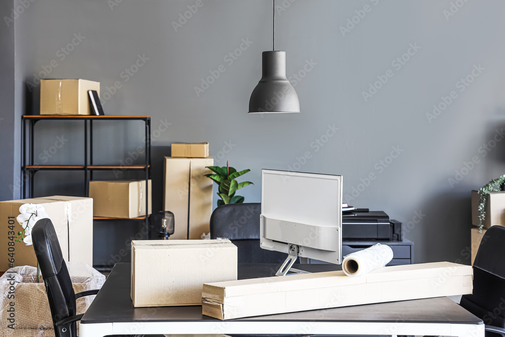 Interior of modern office with cardboard boxes on moving day