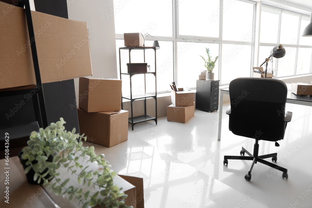 Interior of modern office with cardboard boxes on moving day