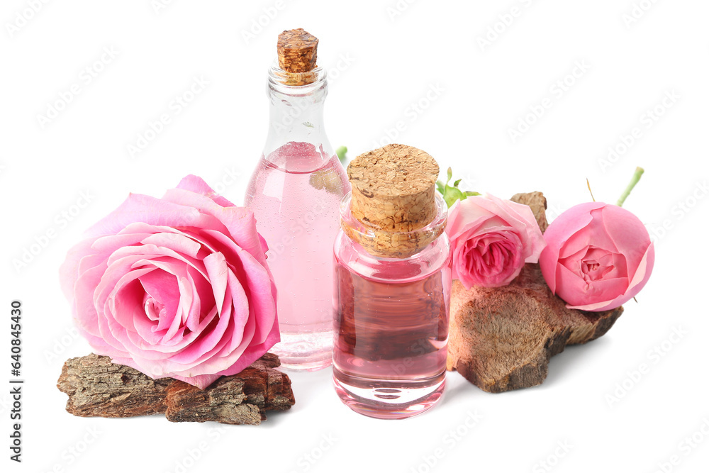 Bottles of cosmetic oil with rose extract and flowers on white background