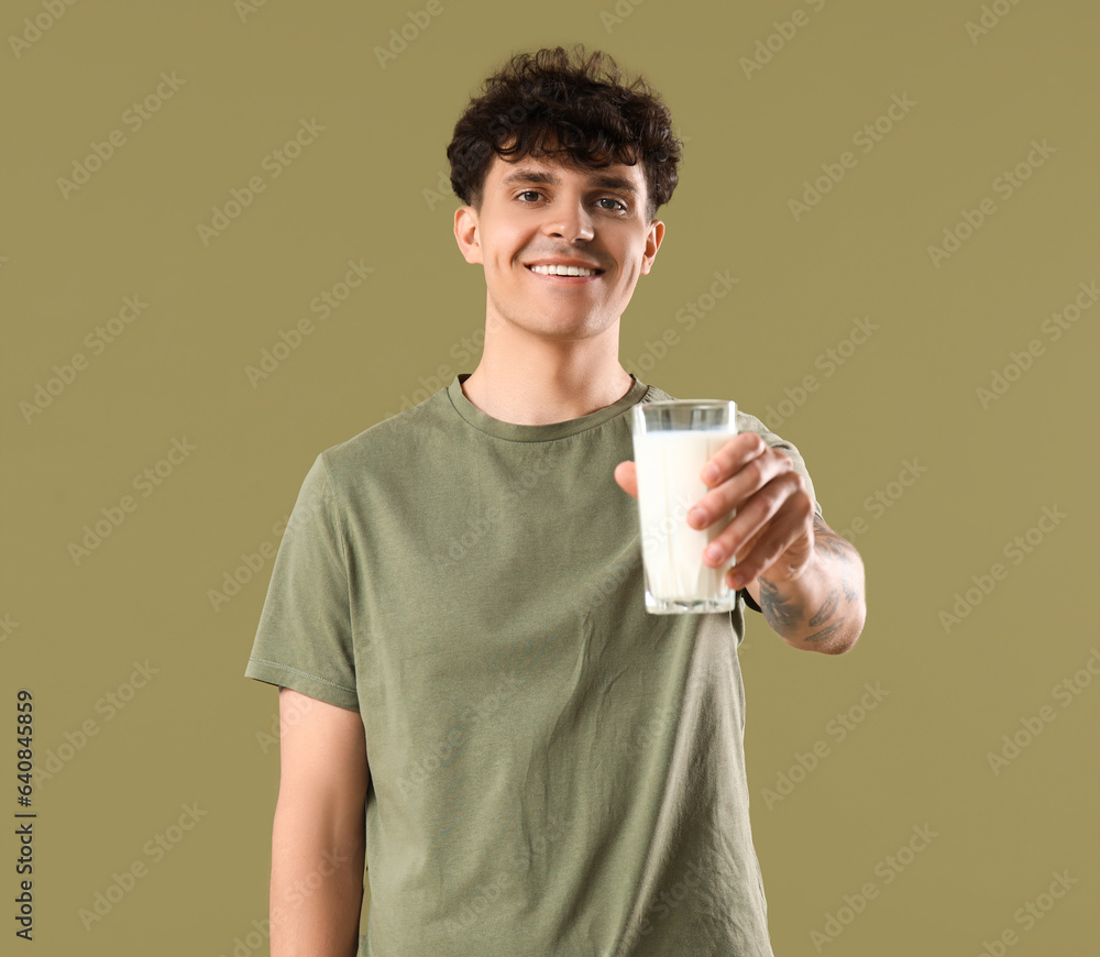 Young man with glass of milk on green background