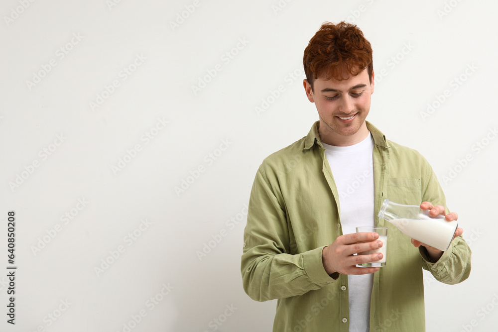 Young man with glass of milk on white background