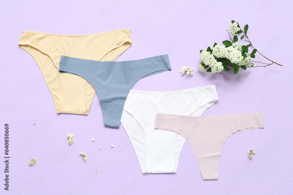 Set of stylish female panties and blooming plant branch on color background