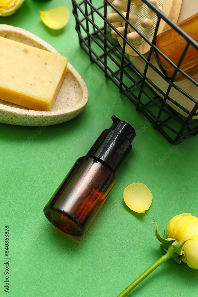 Bottle of cosmetic product, soap bar and flower on color background