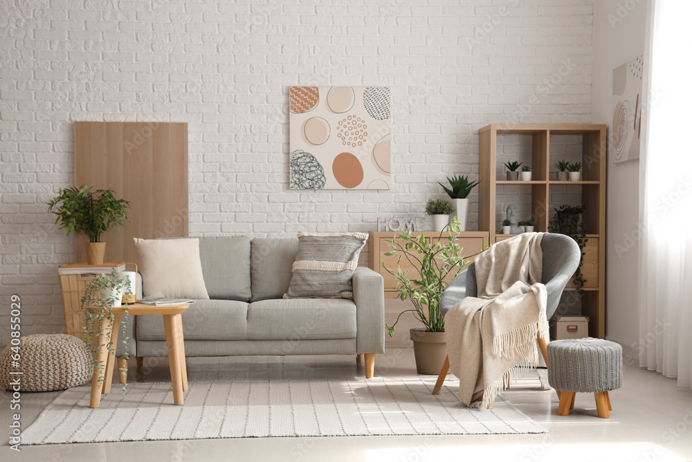 Interior of light living room with cozy grey sofa, armchair and coffee table