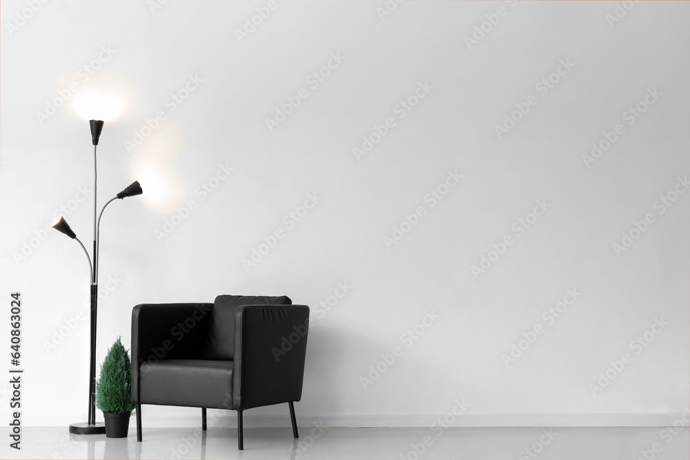 Glowing lamp with armchair and houseplant in light room