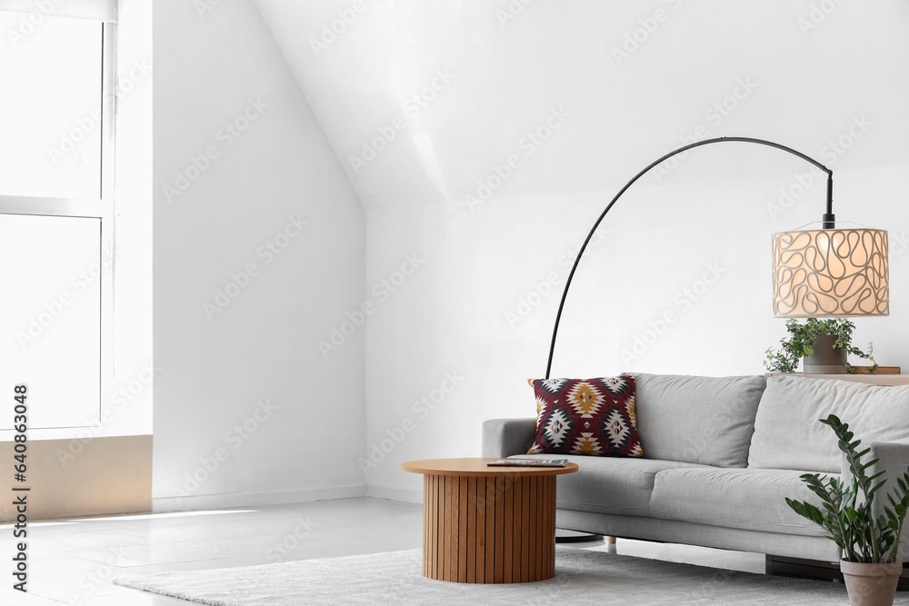 Interior of light living room with lamp, sofa and table