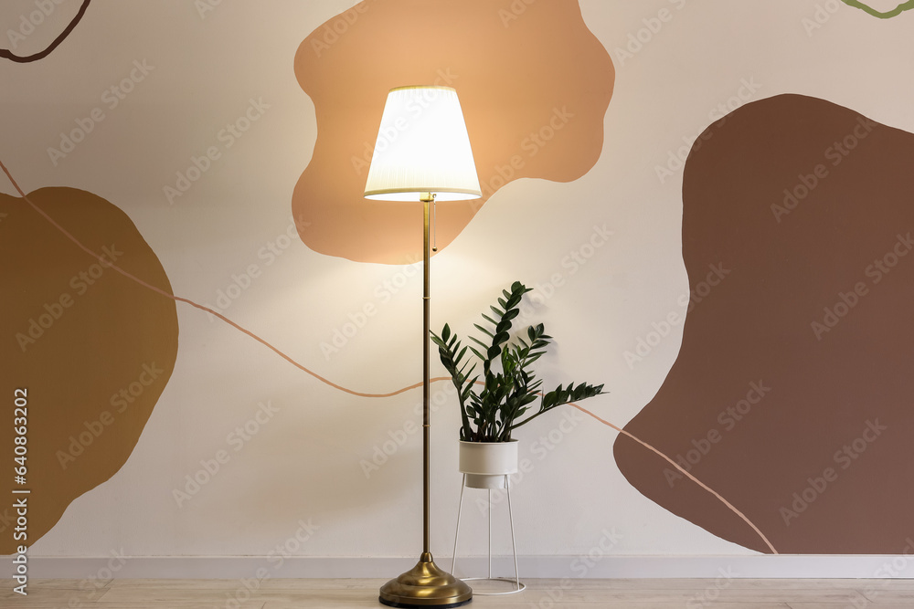 Glowing stand lamp with houseplant in room