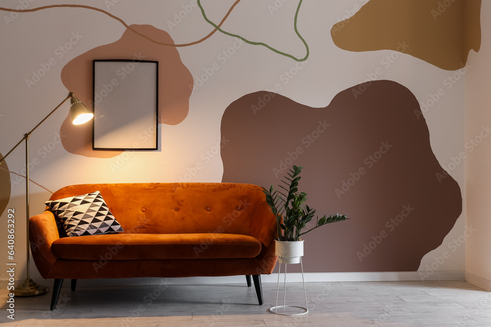 Interior of living room with glowing stand lamp and red sofa