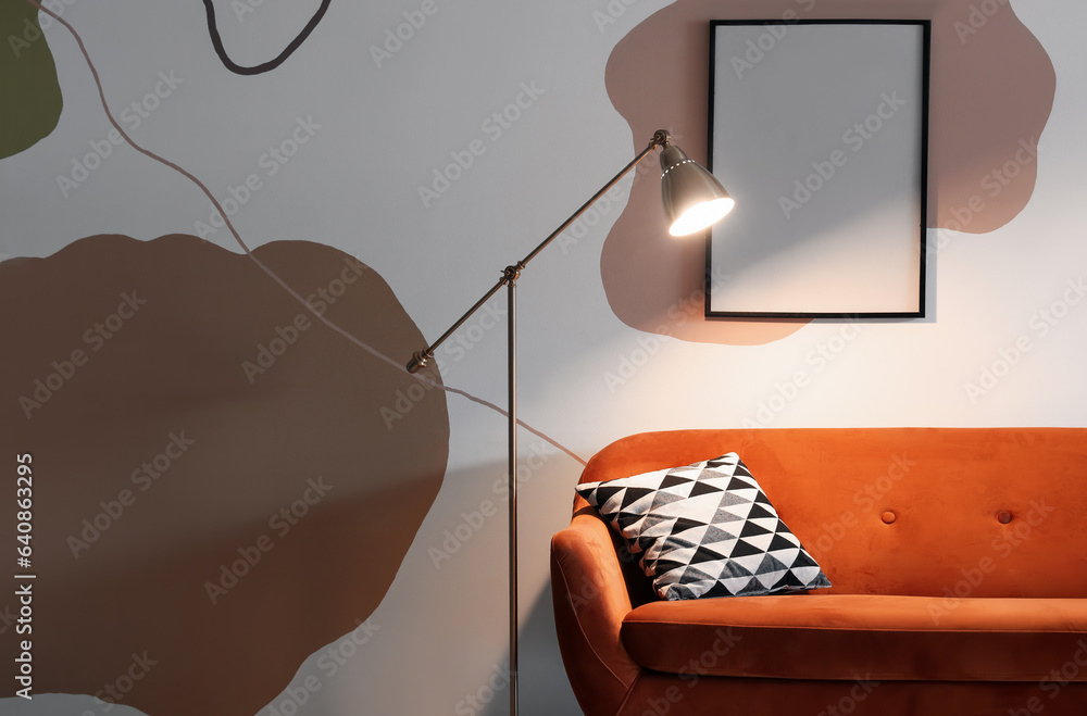 Interior of living room with glowing stand lamp and red sofa