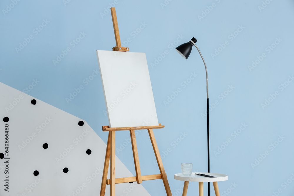 Lamp and easel near blue wall