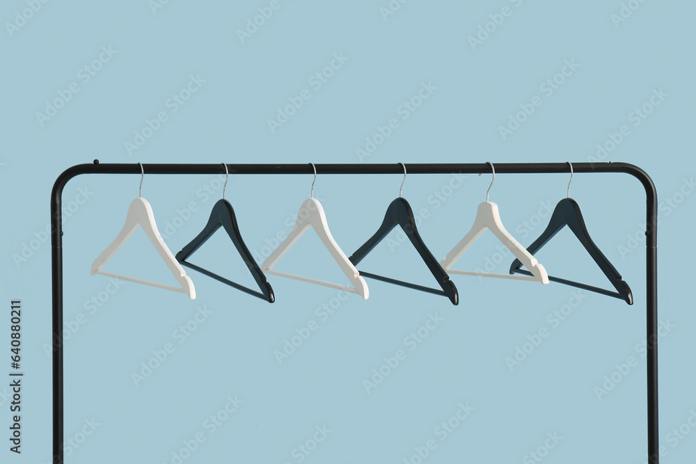 Rack with wooden clothes hangers on blue background