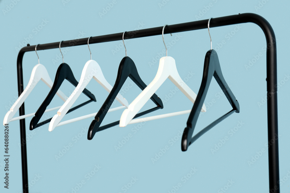 Rack with wooden clothes hangers on blue background