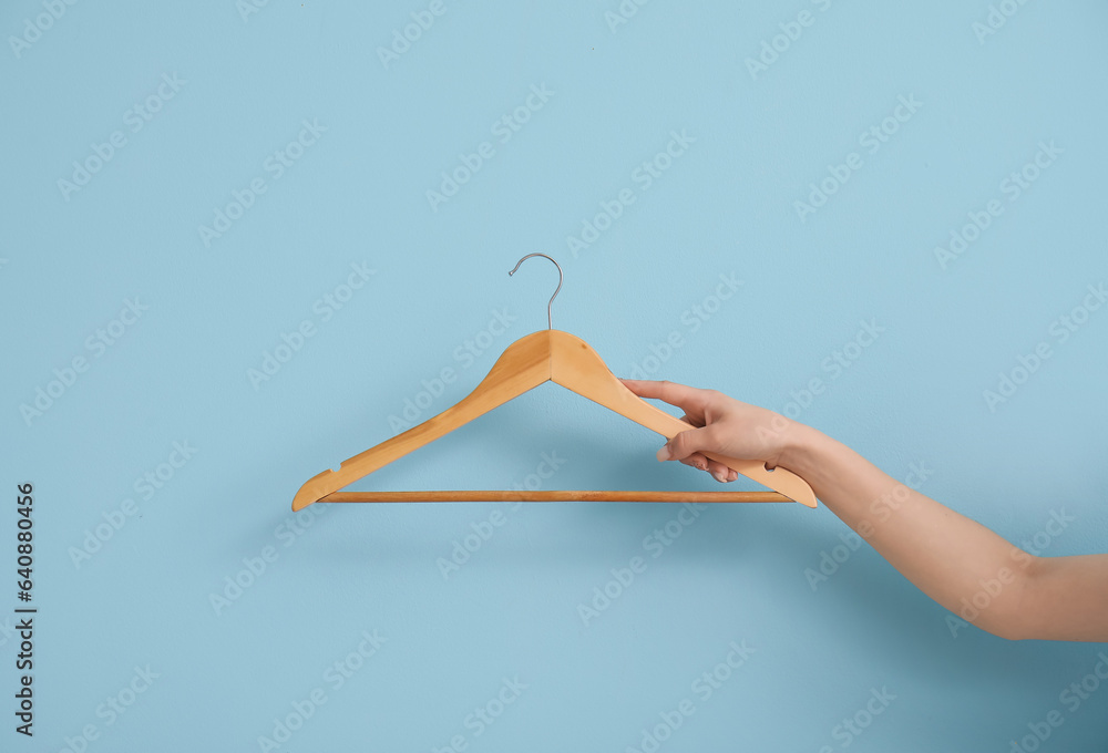 Woman holding wooden clothes hanger on blue background