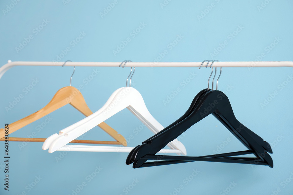 Rack with wooden clothes hangers on blue background