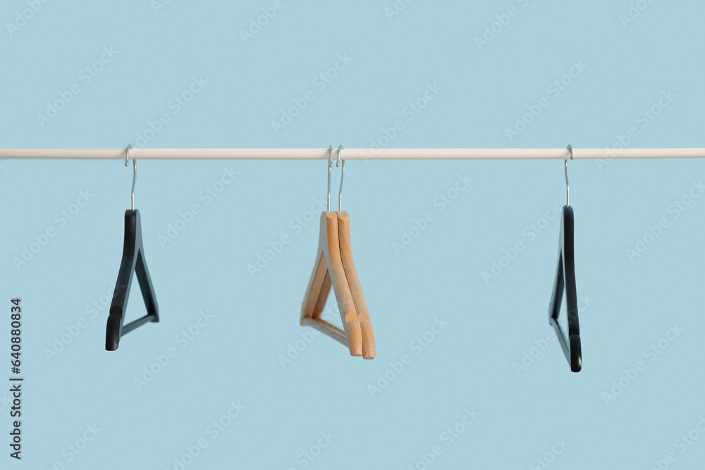 Rack with wooden clothes hangers on blue background