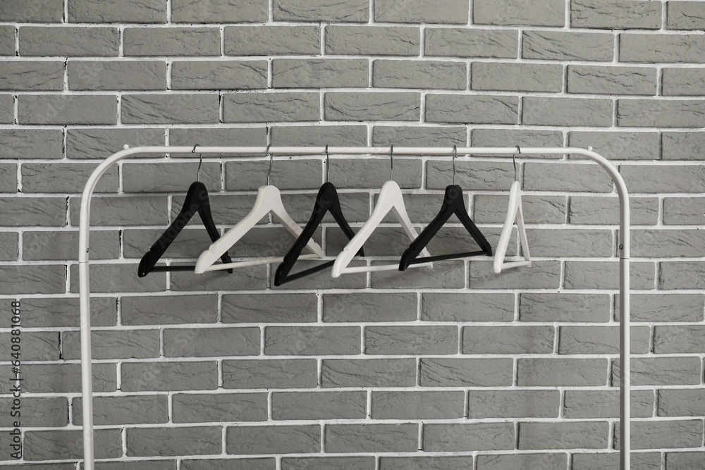 Rack with wooden clothes hangers on grey brick wall background