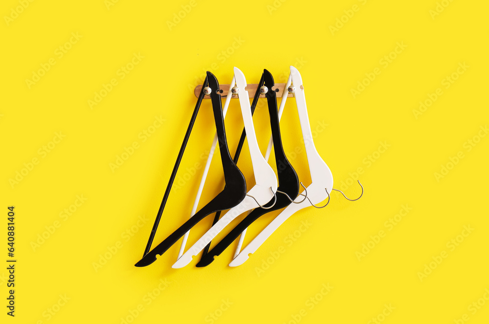 Rack with wooden clothes hangers on yellow background