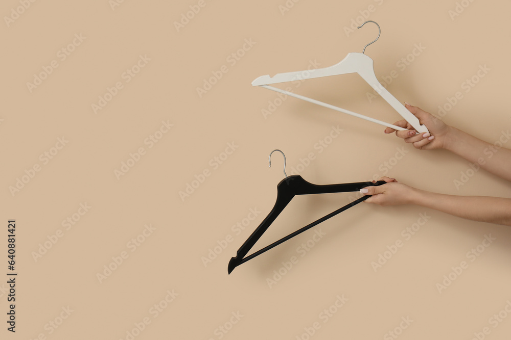 Woman holding wooden clothes hangers on beige background