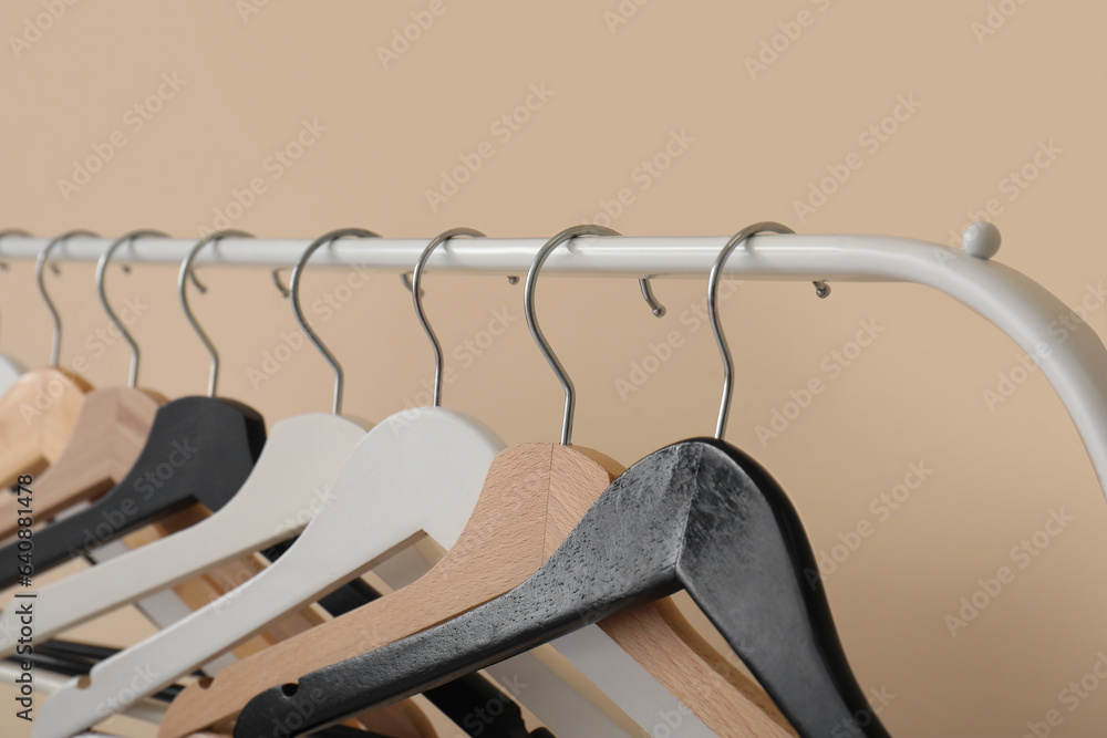 Rack with wooden clothes hangers on beige background