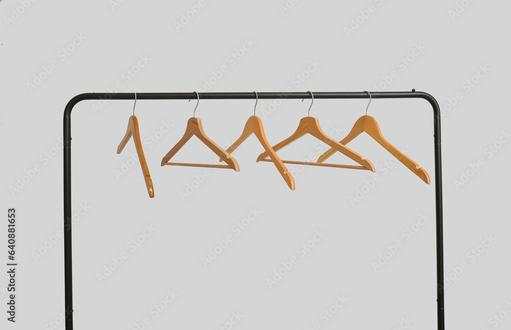 Rack with wooden clothes hangers on grey background