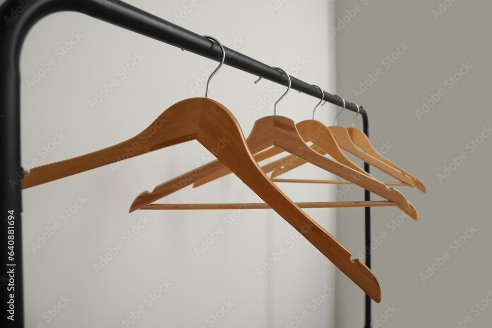 Rack with wooden clothes hangers on grey background